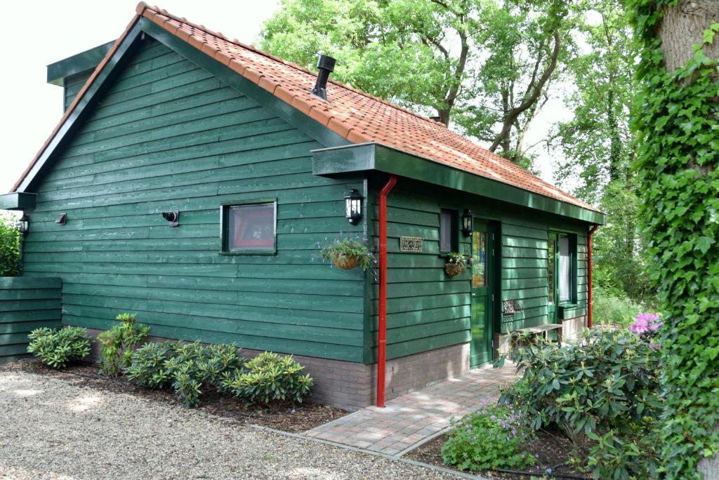 a green house with a red roof at Gastenverblijf Kleinkamperfoelie in Gorssel