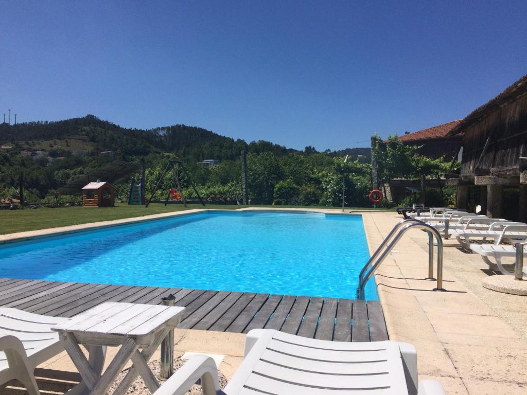 a swimming pool with white chairs and a bunch ofitures at Quinta Travessa in Vieira do Minho