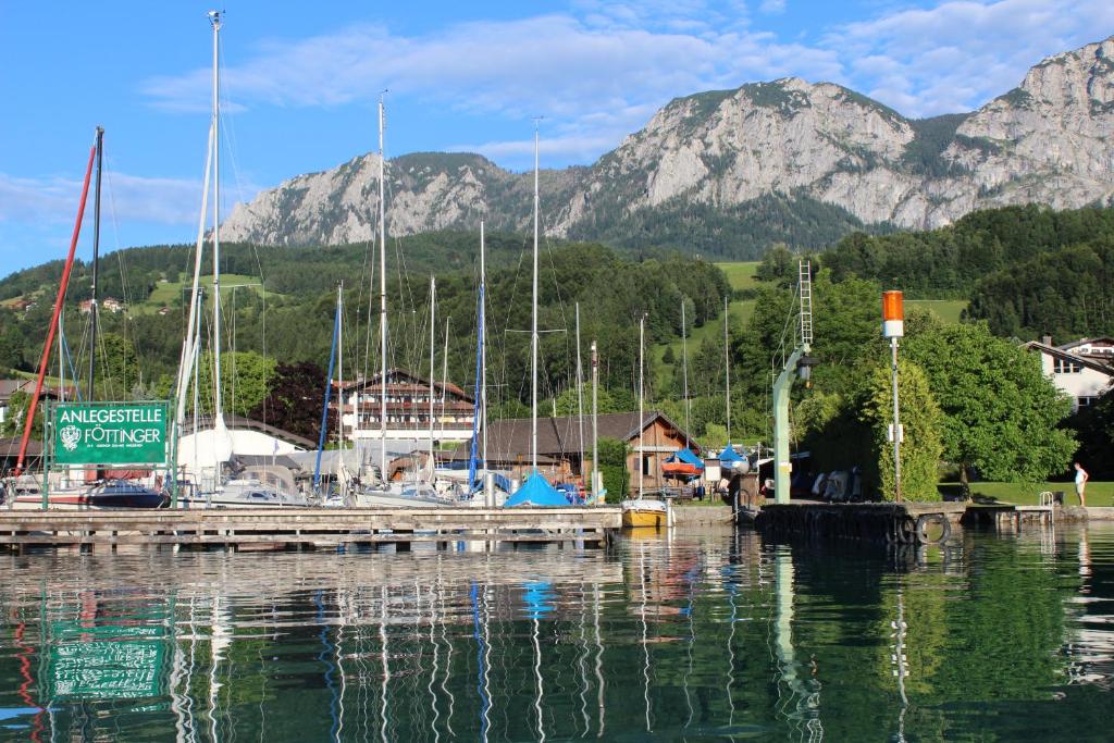 a marina with boats in the water with mountains in the background at Aktivhotel Föttinger in Steinbach am Attersee