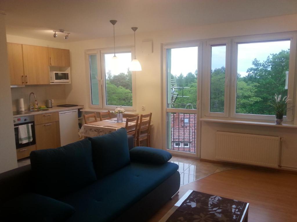 a living room with a blue couch and a kitchen at Apartament Rega Mrzeżyno in Mrzeżyno