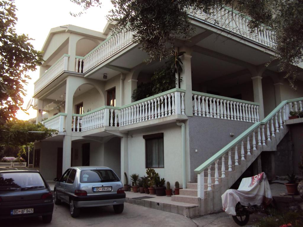 uma casa branca com dois carros estacionados em frente em Apartments Papan em Petrovac na Moru