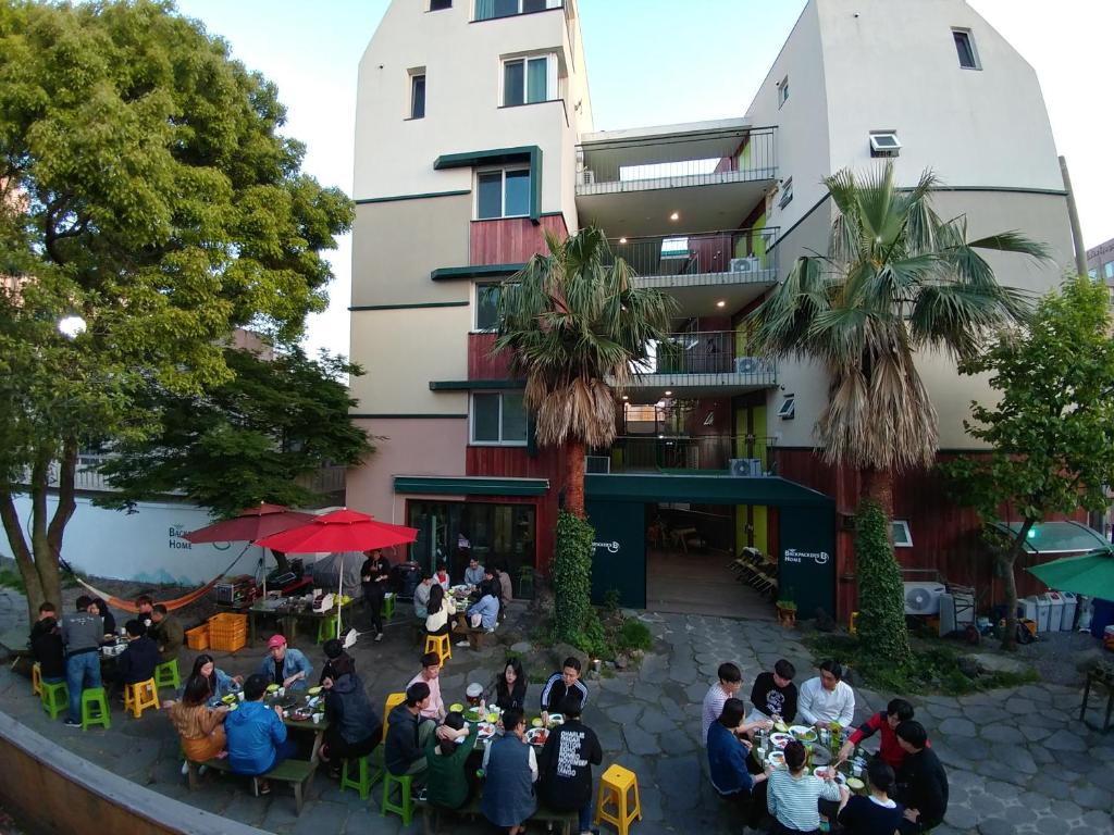 西归浦市背包客之家旅馆的一群人坐在建筑物前的桌子旁