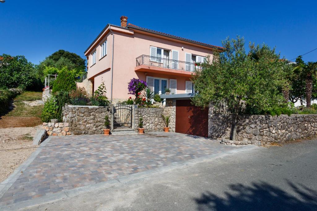 a house with a stone wall and a driveway at Apartmani Anica in Risika