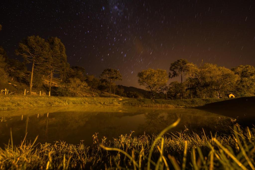 una noche estrellada sobre un estanque en un campo en Pousada Recanto da Serra - Unidade Campestre en Urubici