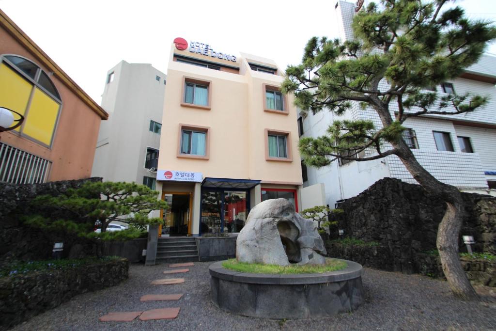 uma estátua em frente a um edifício com uma árvore em Daedong Hotel em Jeju