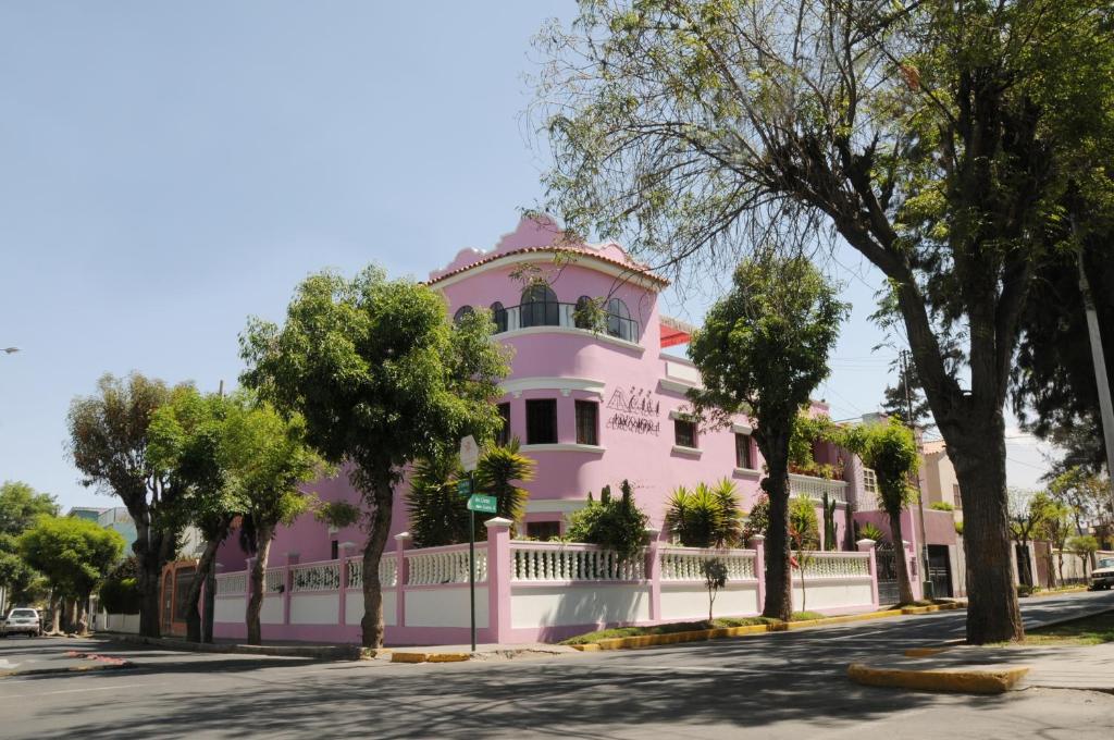 a pink house with a white fence on a street at Casa Arequipa in Arequipa