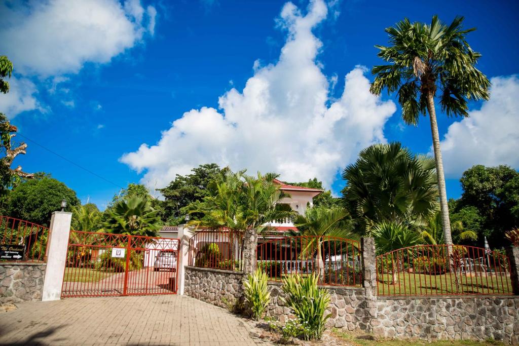 une maison avec une clôture et des palmiers dans l'établissement The Orchard Holiday Home, à Mahé