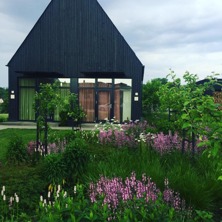 a black house with a garden with purple flowers at Domi Lini in Druskininkai