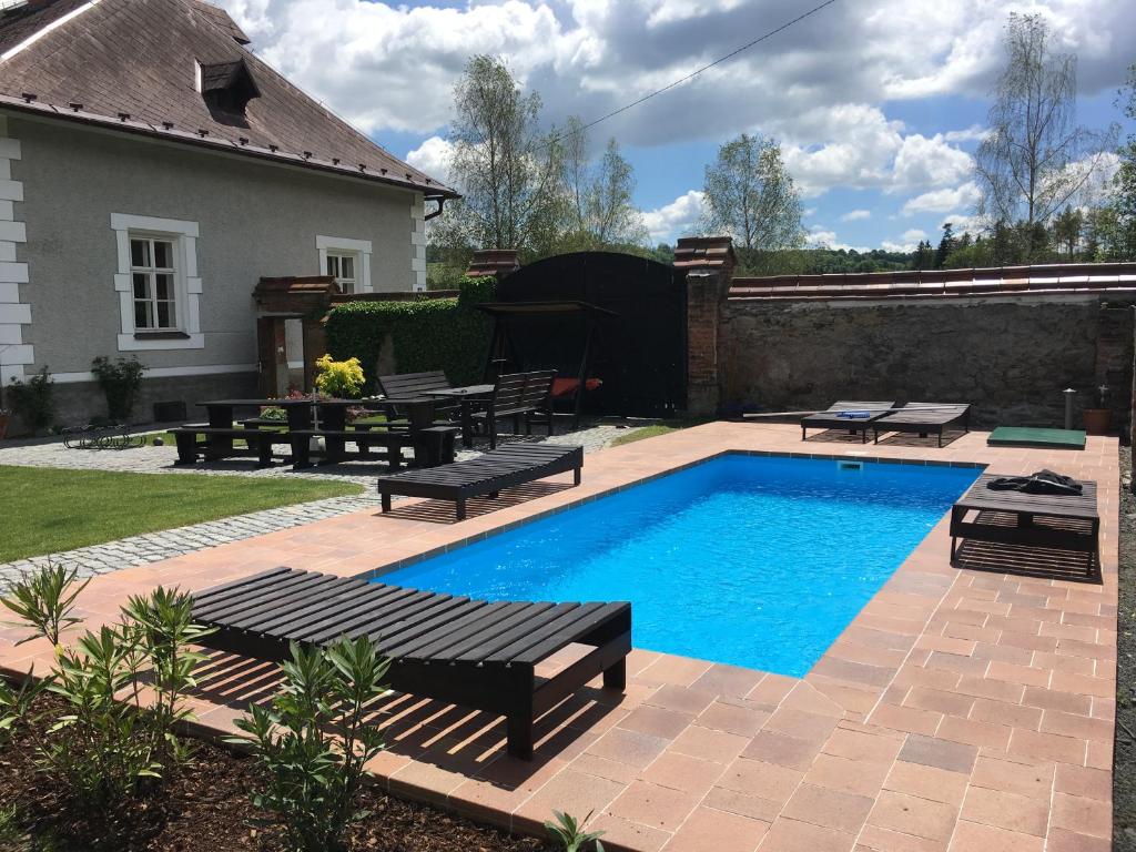 a swimming pool in a yard with benches and a house at Chalupa Volárna in Roudno