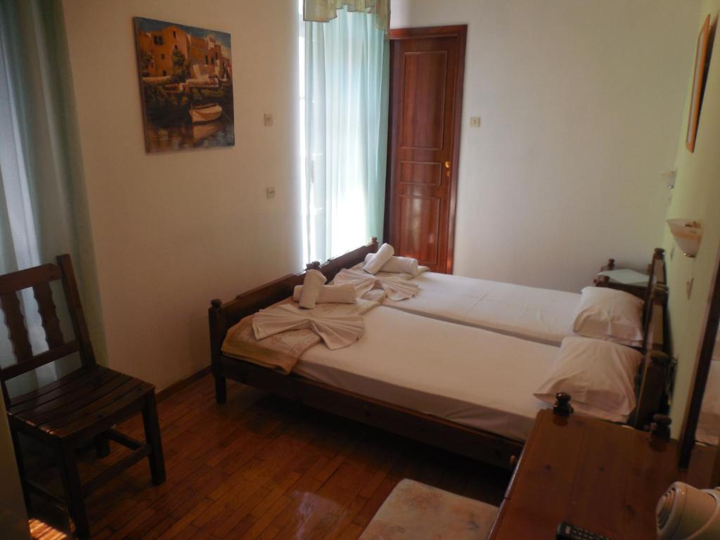a bedroom with a bed and a chair and a window at Adonis Rooms in Skopelos Town
