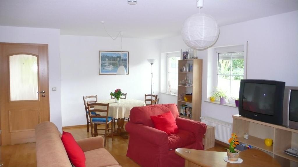 een woonkamer met een rode bank en een tv bij Ferienwohnung Gisela in Bausendorf