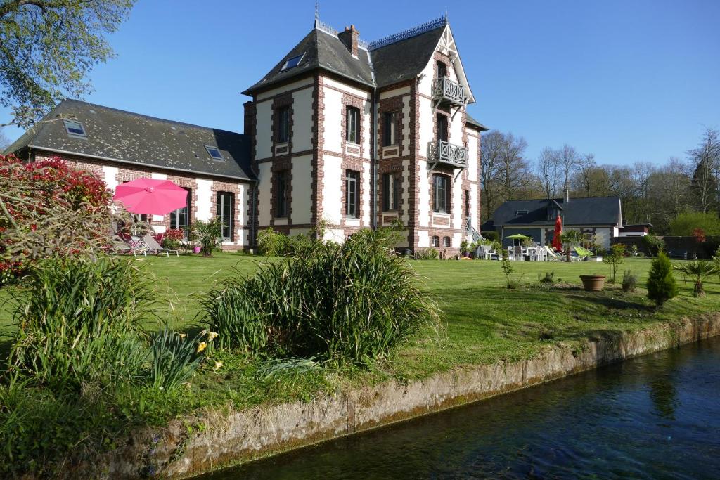 un vieux bâtiment avec une rivière devant lui dans l'établissement Villa Argonne, à Ouville-la-Rivière