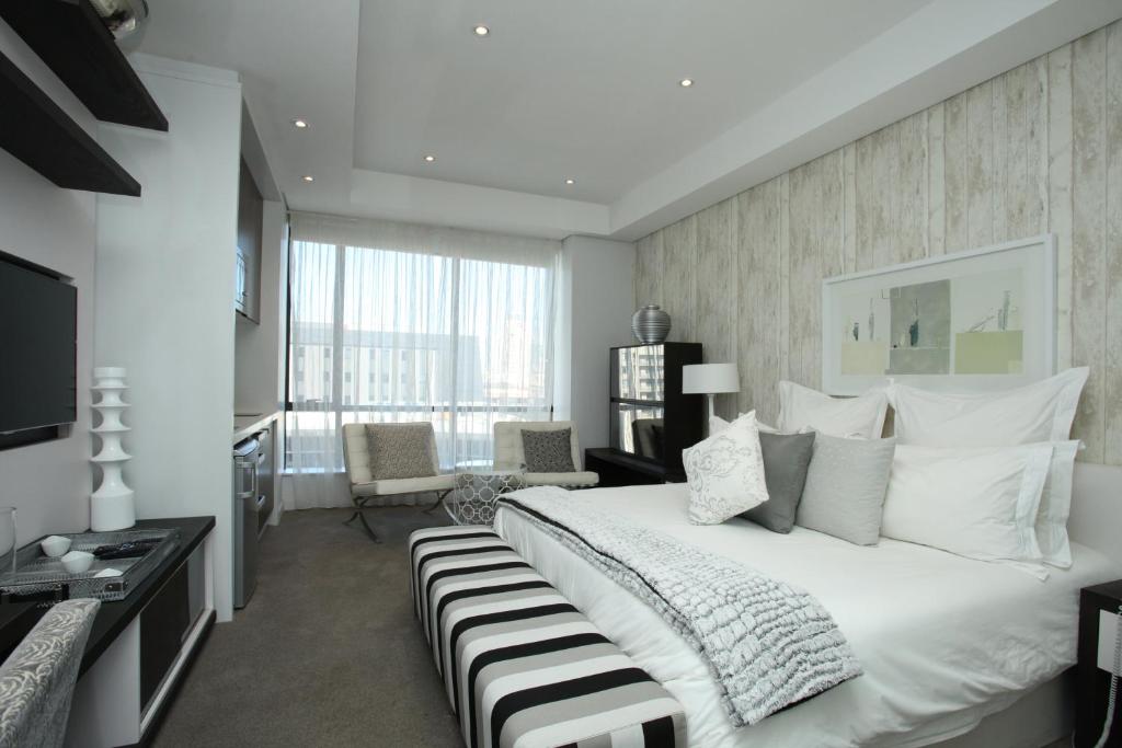 a bedroom with a large white bed and a desk at Luxury @ Sandton Skye in Johannesburg