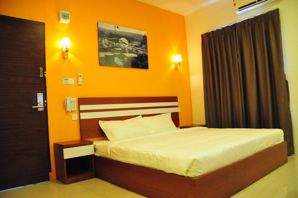a bedroom with a bed with an orange wall at Venia Hotel Batam - CHSE Certified in Sagulung