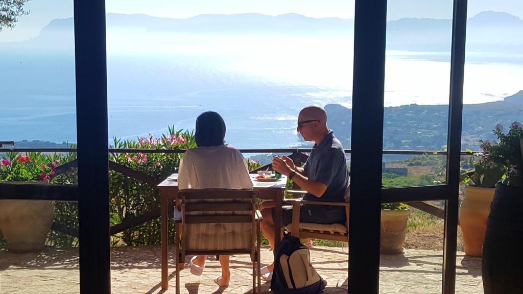a man and a woman sitting at a table with a view at B&B Tre Giummare in Scopello
