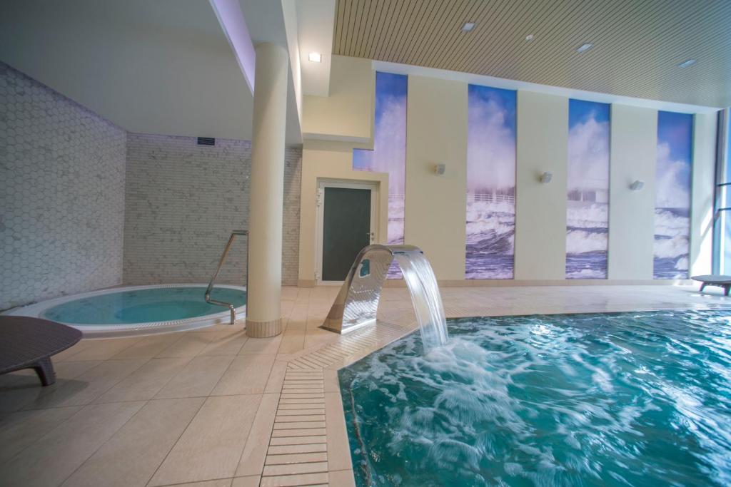 een zwembad met een hot tub in een gebouw bij SeaPark Hotel Wellness & Spa in Kołobrzeg