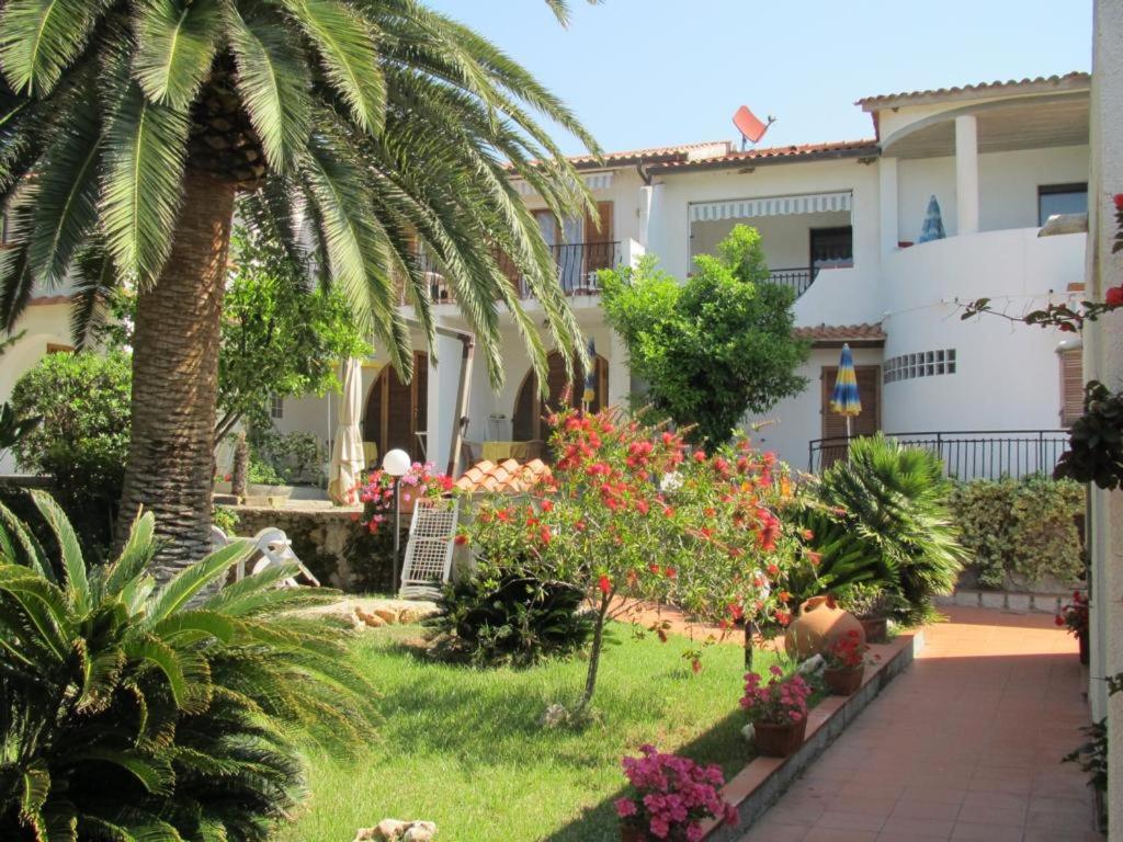 a garden in front of a house with palm trees at Al Pozzo Residence in Capoliveri