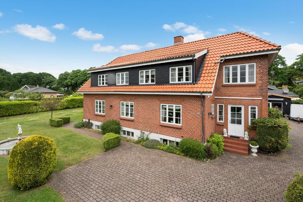 una casa de ladrillo rojo con techo naranja en Kollund Rooms, en Kollund Østerskov