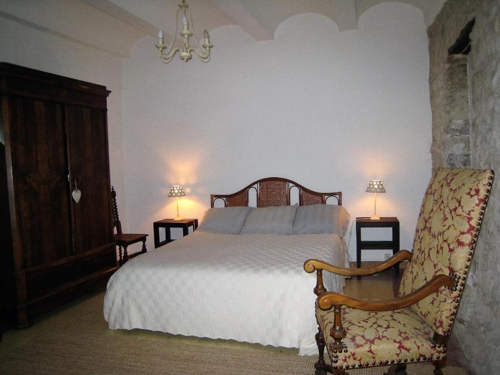 a bedroom with a bed and a chair and lights at Gite du Boulidou in Cazilhac