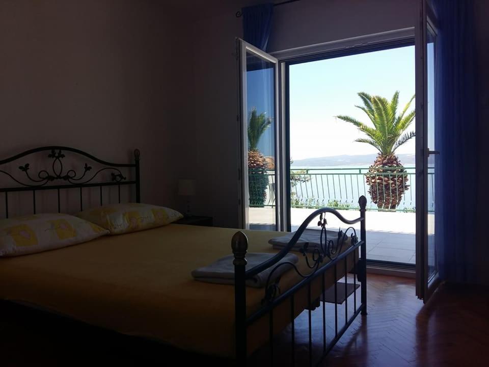 a bedroom with a bed with a view of the ocean at Apartments Tri Palme in Baška Voda