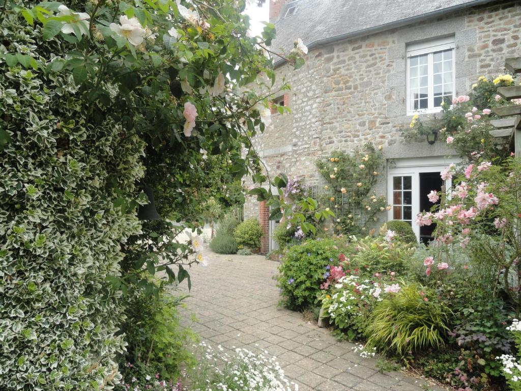 a brick house with a garden of flowers and plants at La Haute Gilberdière in Sartilly
