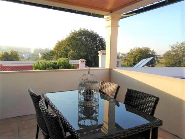 una mesa de cristal con sillas y una jaula de aves en el balcón en Casa Monte Alegre, en Redinha