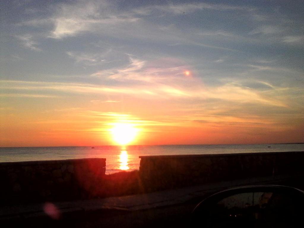 a sunset on the beach with the sun in the sky at Monolocali Angelica in Porto Cesareo