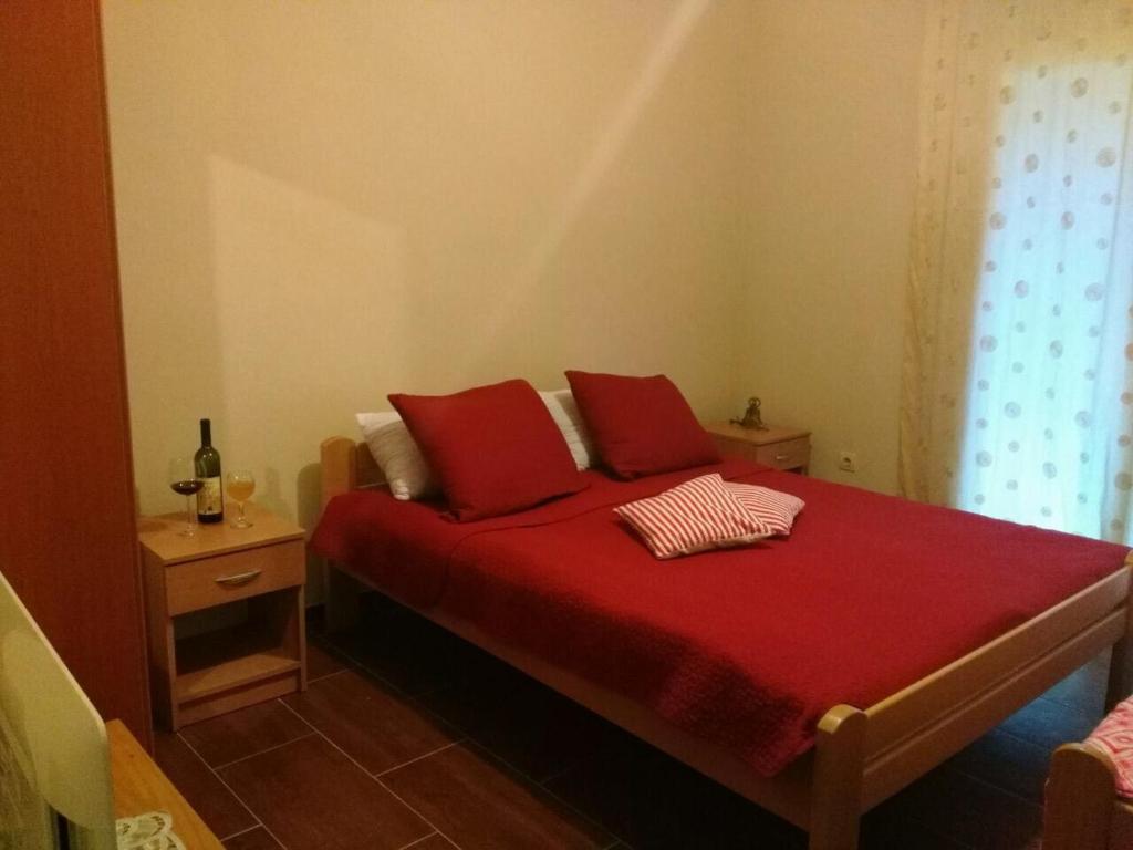 a bedroom with a red bed with two red pillows at Apartmani Cuce in Kotor
