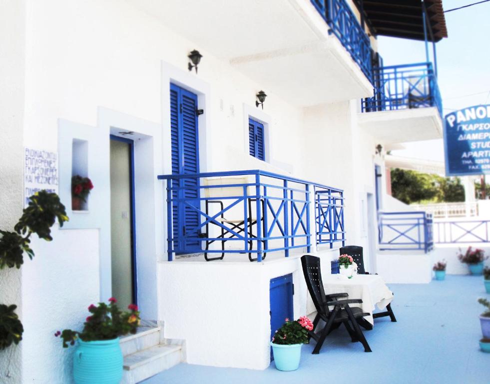 a white building with blue balconies and a table and chairs at Angistri's panorama apartments in Skala