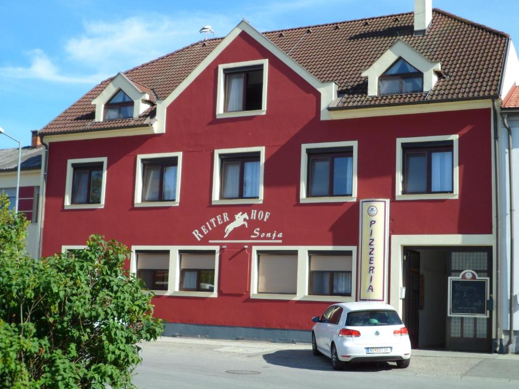 ein rotes Gebäude mit einem Auto vor der Tür in der Unterkunft Reiterhof Sonja in Apetlon