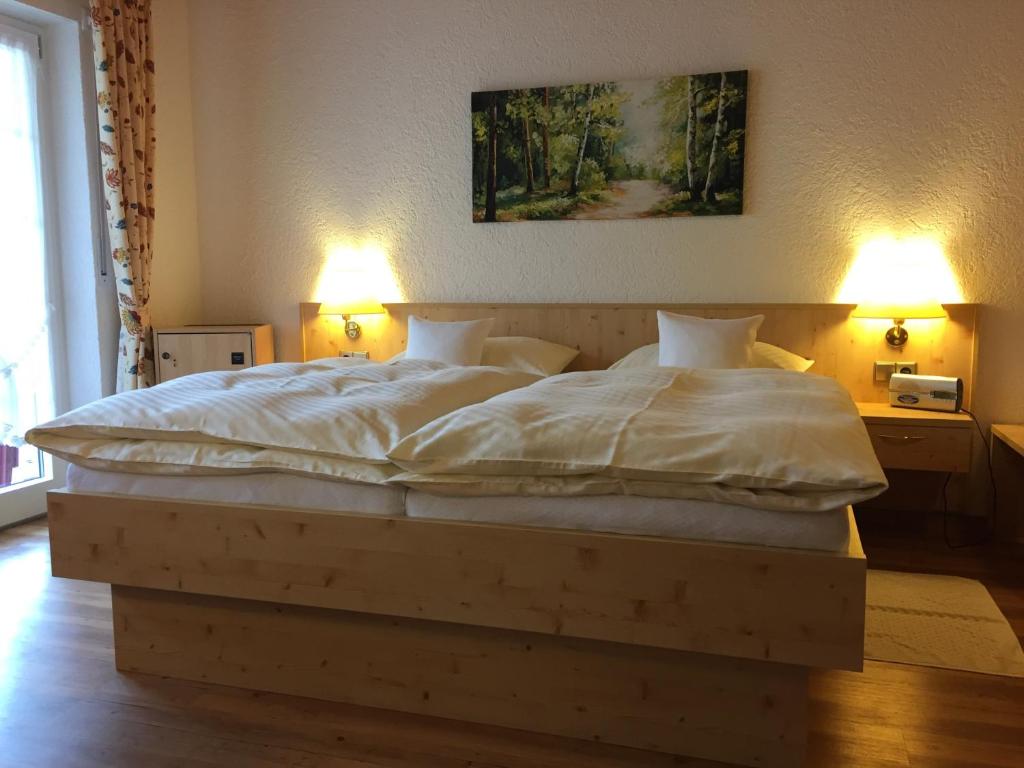 una camera da letto con un grande letto con lenzuola e cuscini bianchi di Pension Glöcklehof a Todtnauberg