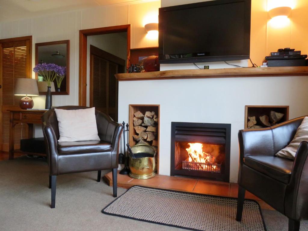 a living room with two chairs and a fireplace at Coromandel Apartments in Coromandel Town