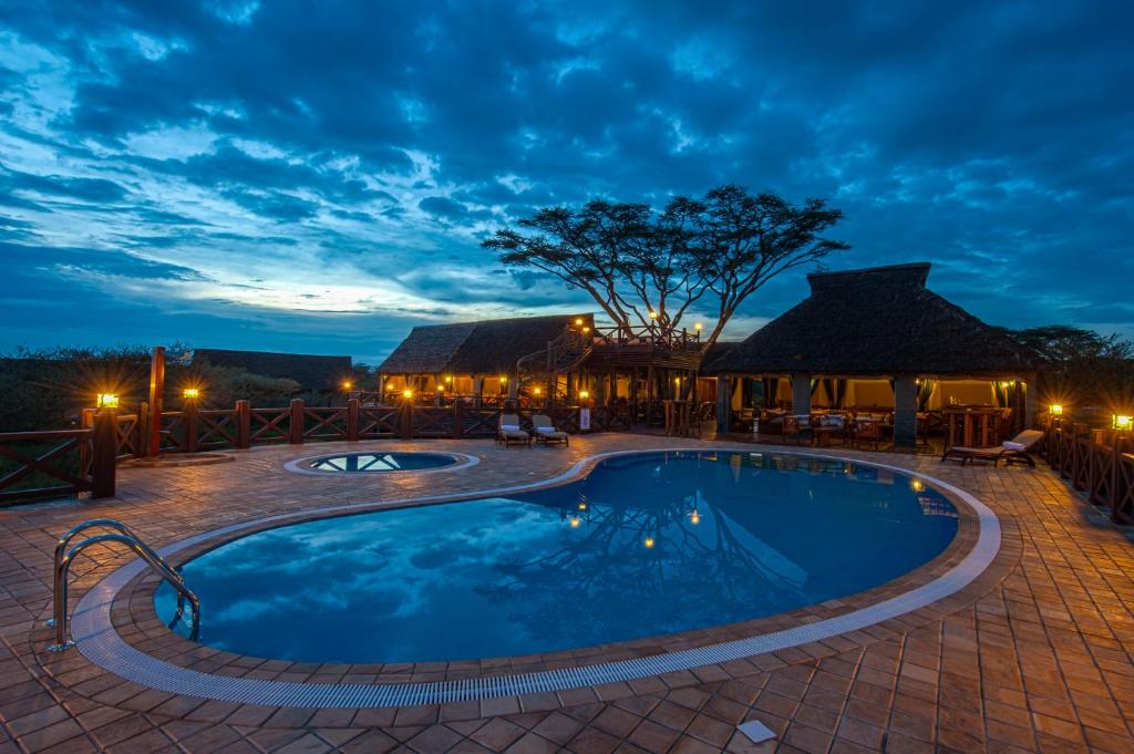 a swimming pool in a resort at night at Lake Ndutu Luxury Tented Lodge in Sinoni
