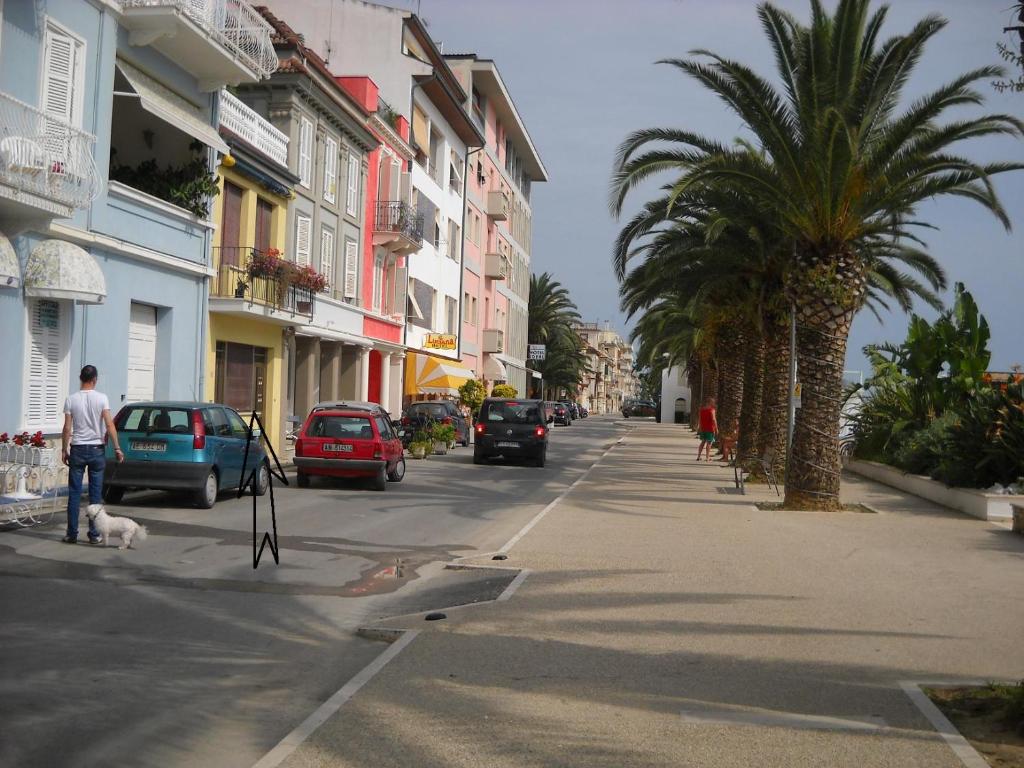 a street with cars and palm trees on a city street at Appartamento Prima Fila mare in Cupra Marittima