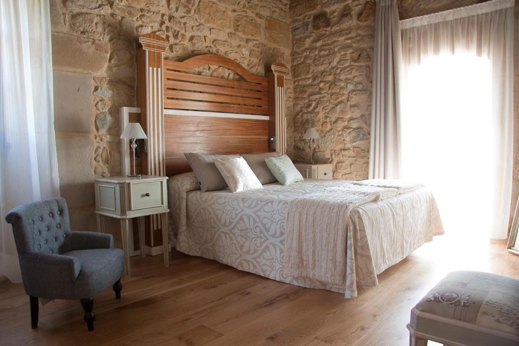 um quarto com uma cama com uma cabeceira de madeira e uma cadeira em Posada La Torre de los Isla & Spa em Beranga