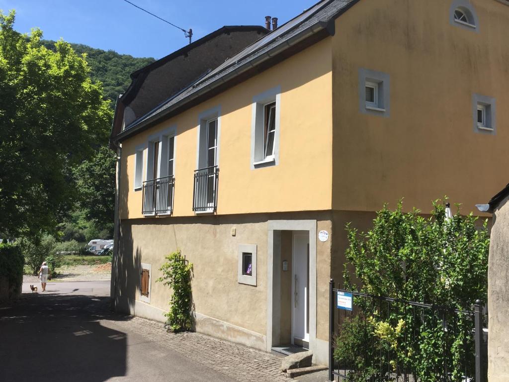 a yellow house with a person walking past it at Ferienhaus Ausonius in Neumagen-Dhron