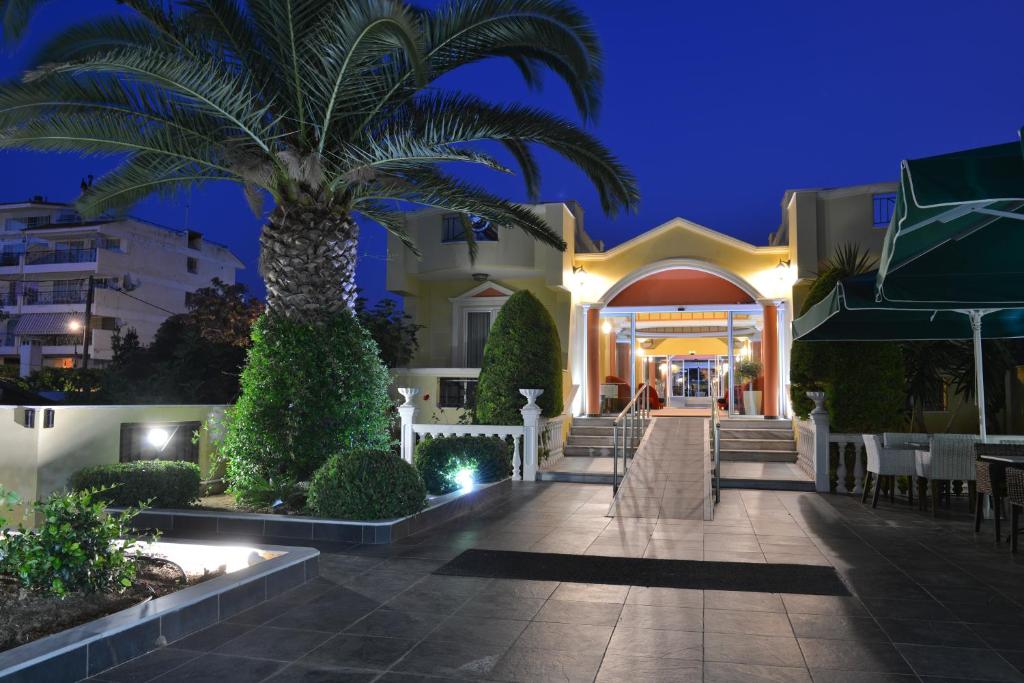 a palm tree in front of a building at night at Hotel Cristina Maris in Loutraki