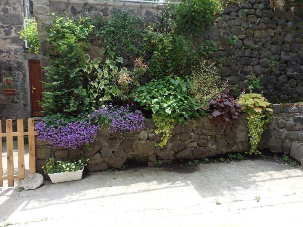 a stone wall with flowers and plants on it at La Maison De Béatrice in Murat