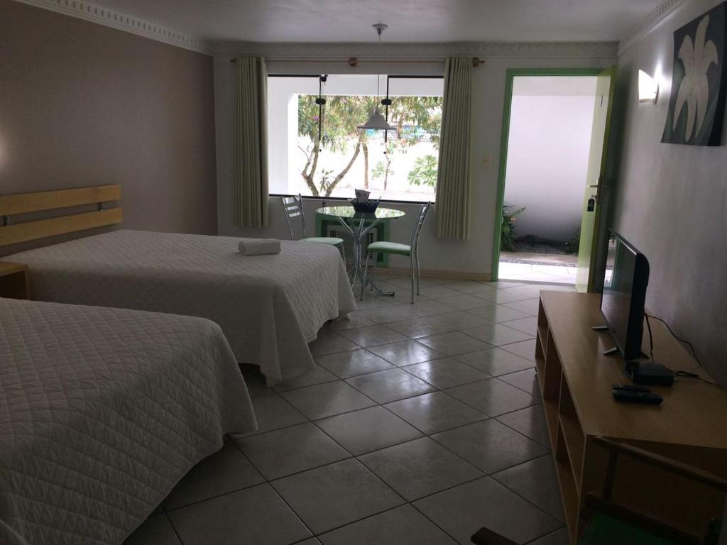 um quarto de hotel com duas camas e uma televisão em Hotel San Bernardino em Guaramirim