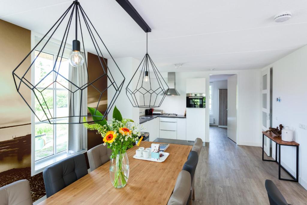 a dining room and living room with a table and flowers at Buitenplaats Witte Raaf aan Zee in Noordwijk