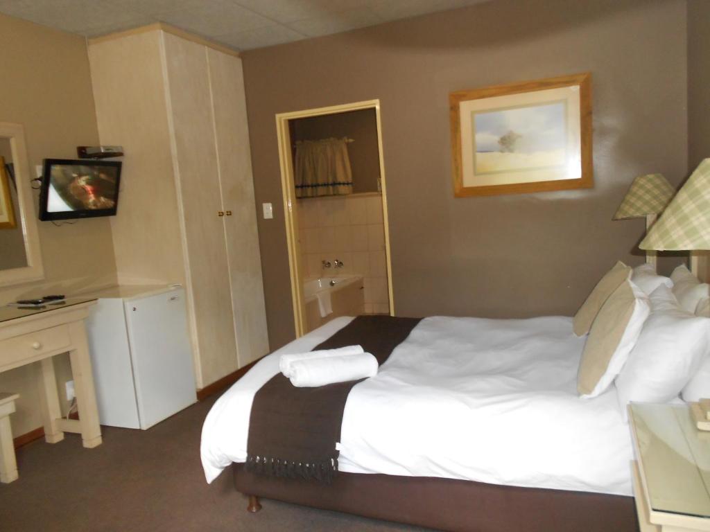 a hotel room with a large bed and a desk at Mountainview Inn in Harrismith