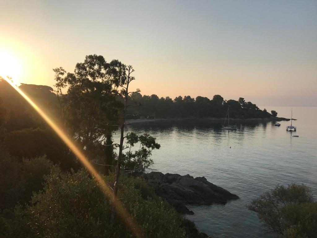 a sunset over a body of water with a boat at Appartements La Fossette plage in Le Lavandou