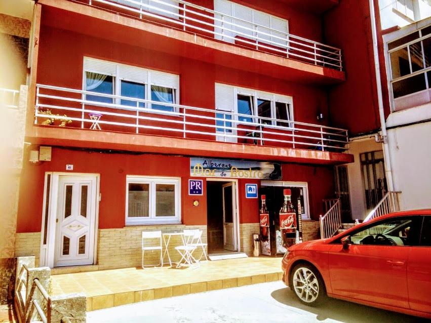 a red building with a car parked in front of it at Albergue Mar de Rostro in Finisterre