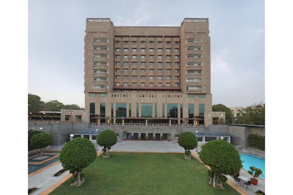 un gran edificio con césped delante en Jaypee Vasant Continental en Nueva Delhi