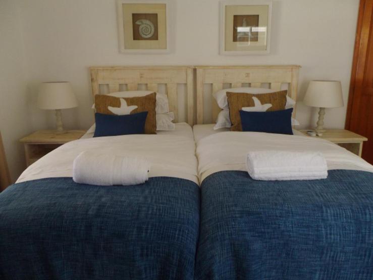 1 dormitorio con 2 camas con sábanas azules y blancas en Breeze Inn Guesthouse, en Kiddʼs Beach
