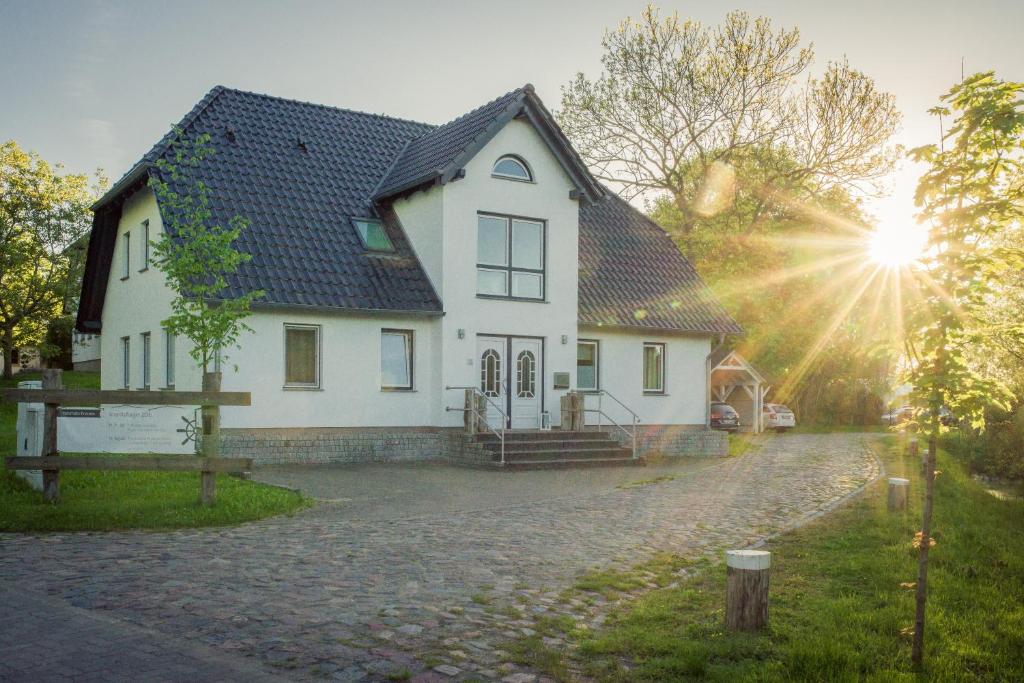 una casa blanca con el sol brillando detrás de ella en Kojenhaus, en Krummin