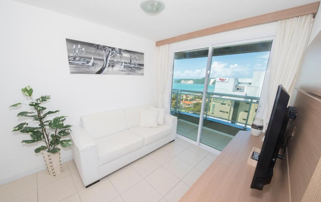 sala de estar con sofá blanco y ventana grande en Ahead Apartment, en Natal