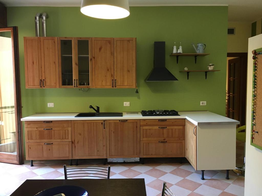 ヴェローナにあるInterno 16の緑の壁と木製のキャビネット付きのキッチン