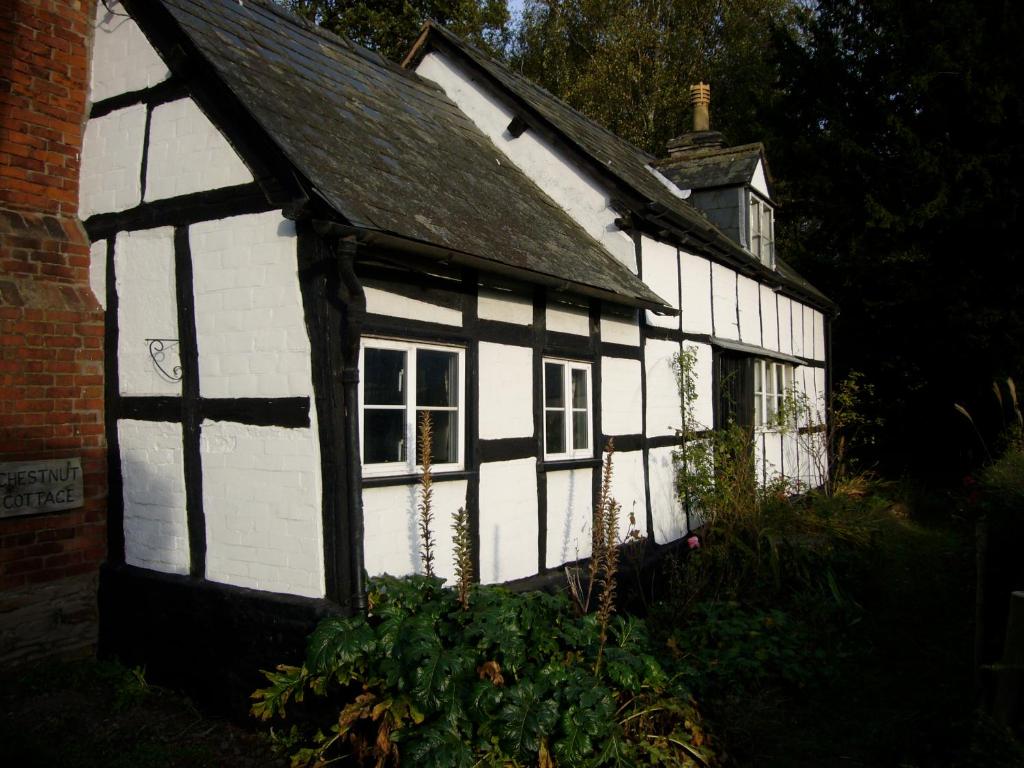 an old white and black house with a window at Chestnut Cottage in Eardisley