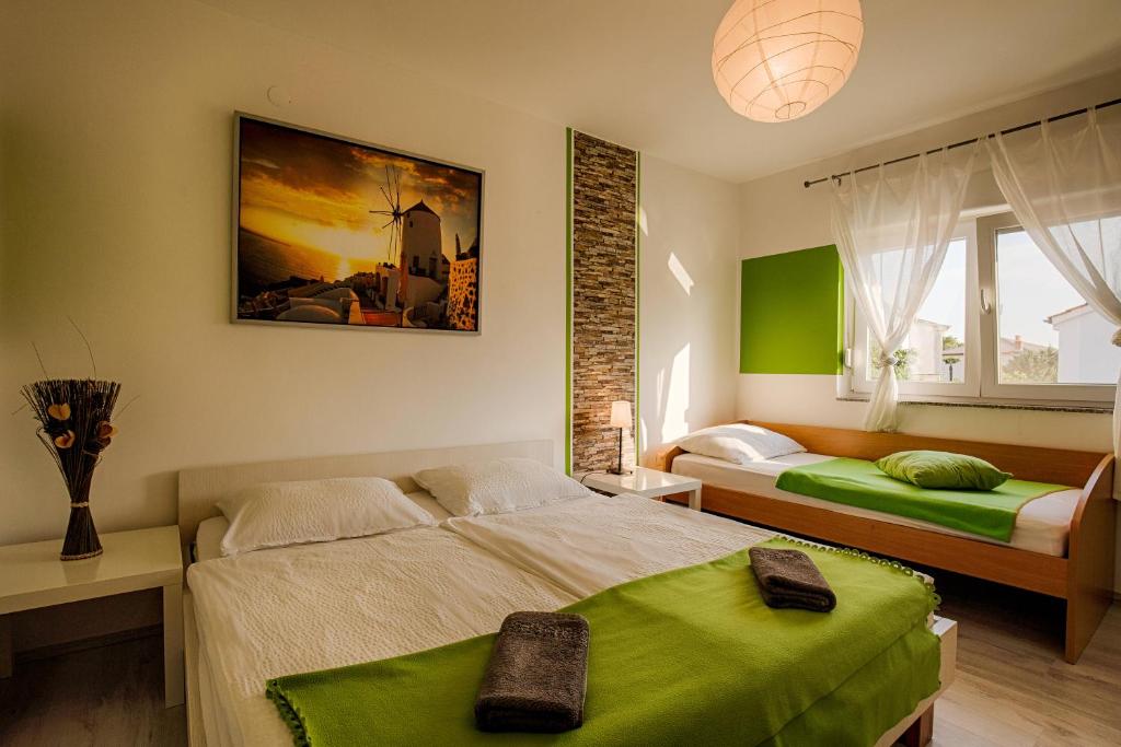 2 Betten in einem Schlafzimmer mit grünen Akzenten in der Unterkunft VilaVeja in Krk